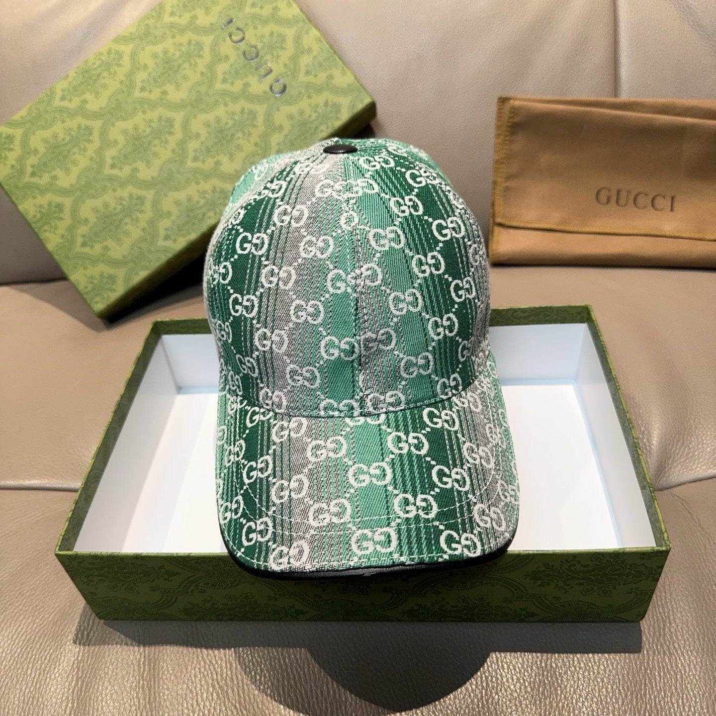 Green Gucci GG monogram baseball cap with metal button and curved brim.