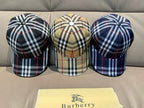 Set of three plaid baseball caps with top buttons; navy and beige check patterns