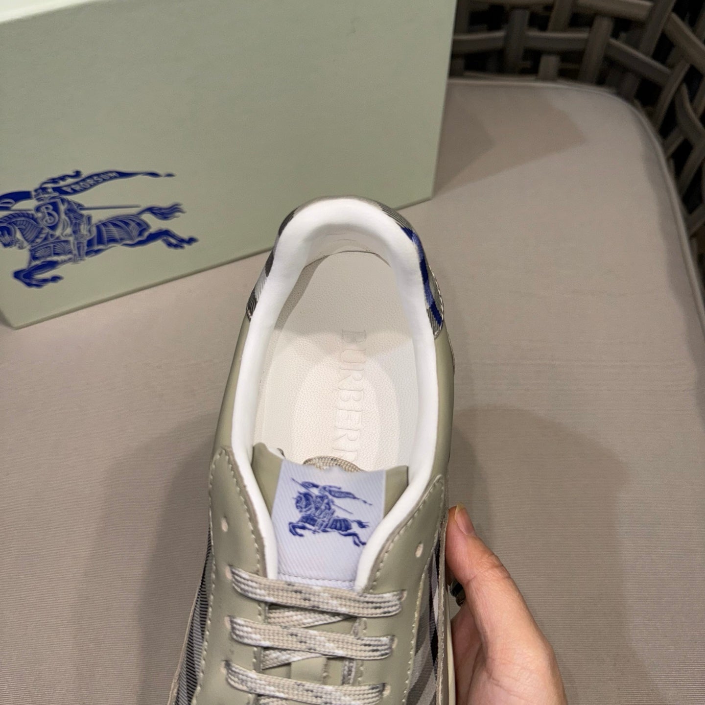 Burberry sneaker close-up at opening, light beige leather with blue logo lining