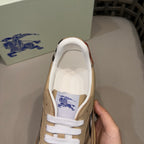 Beige low-top sneaker with white laces and blue logo on tongue