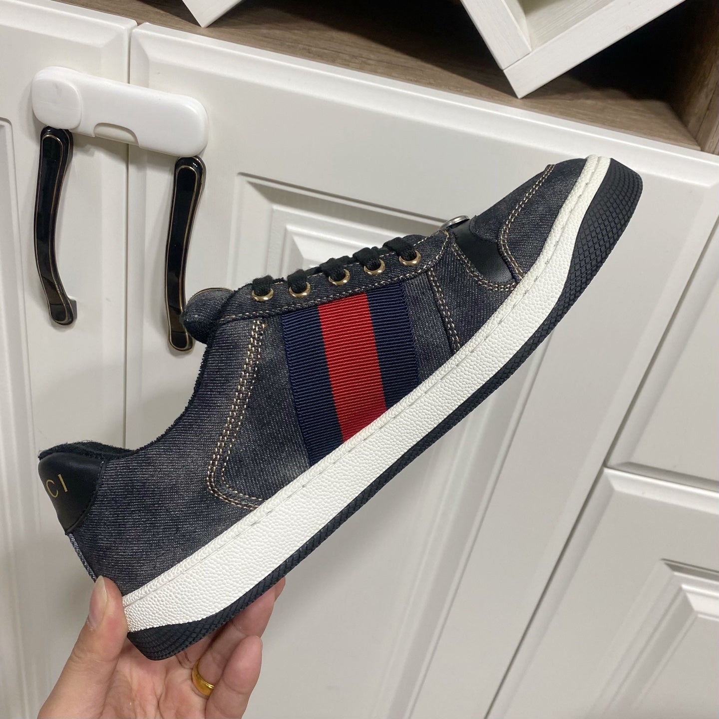 Gucci unisex denim sneaker on hand, dark blue with red-and-blue stripe panel, white sole
