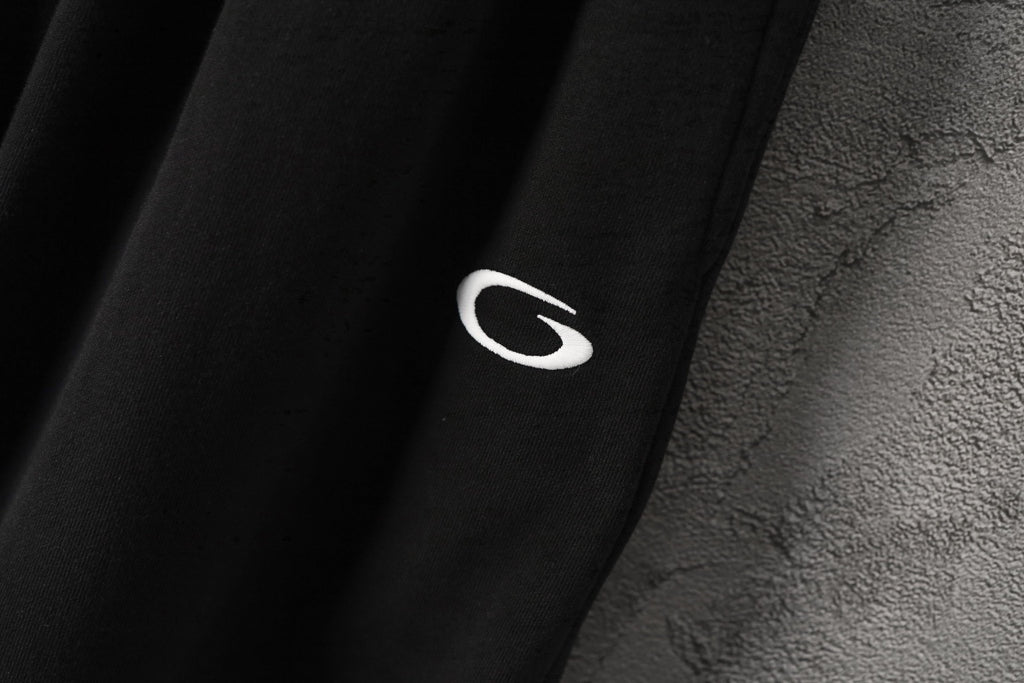 Black pants fabric with small white logo detail