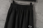Black elastic-waist pants with gathered front and small white logo