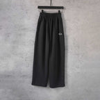 Black drawstring-waist wide-leg pants with small white logo on one thigh