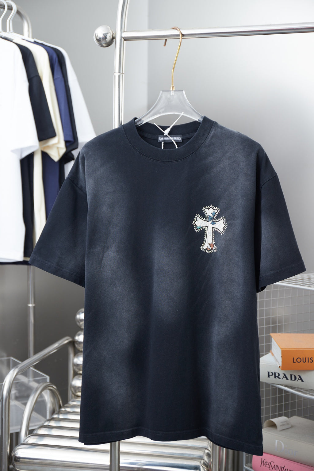Dark short-sleeve T-shirt with small cross logo on the chest.
