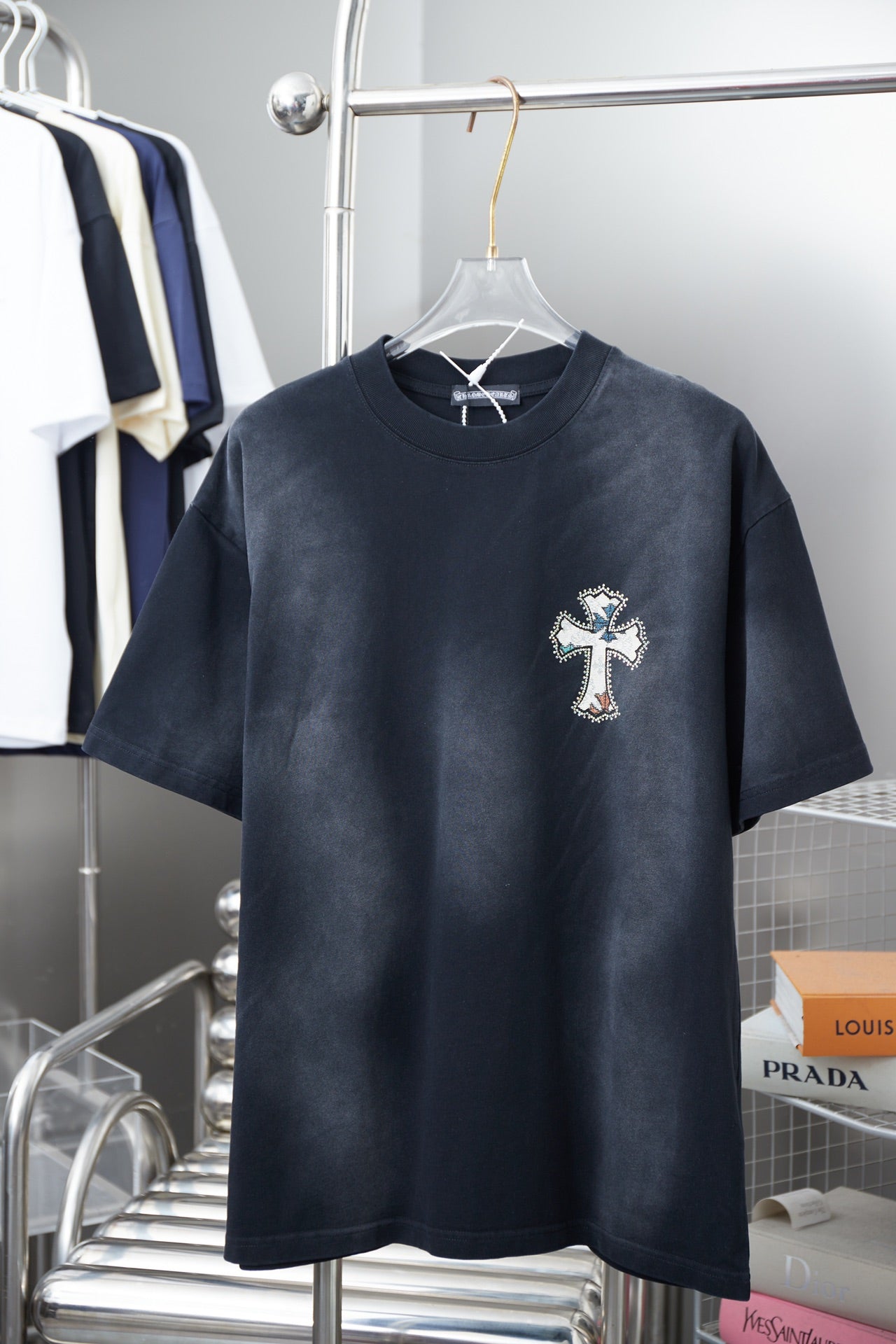 Dark short-sleeve T-shirt with small cross logo on the chest.