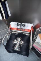Folded T-shirts on a rack: dark and white, each with a cross graphic.