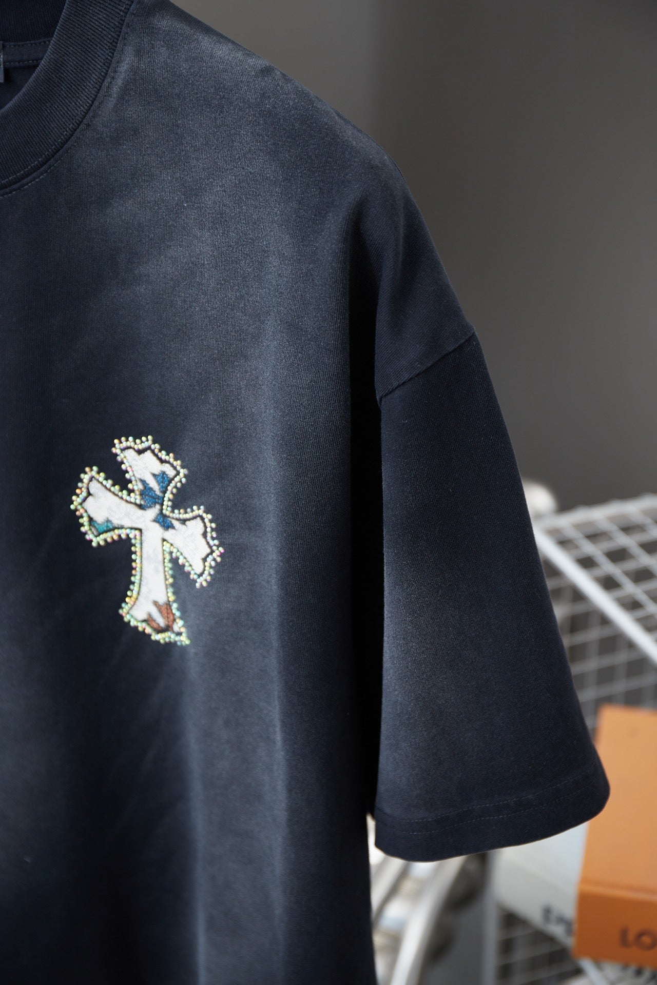 Dark short-sleeve T-shirt sleeve with small cross emblem embroidery.