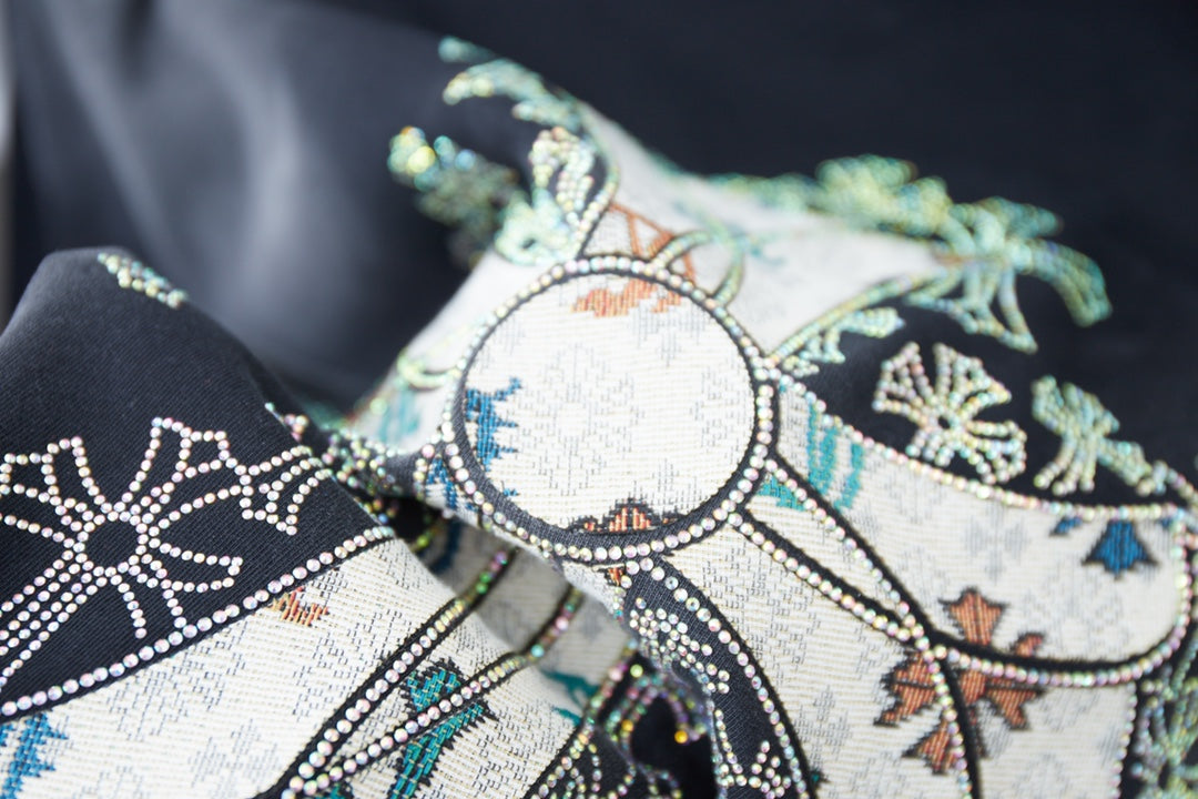 Embroidered cross graphic on dark T-shirt with bead-like accents.
