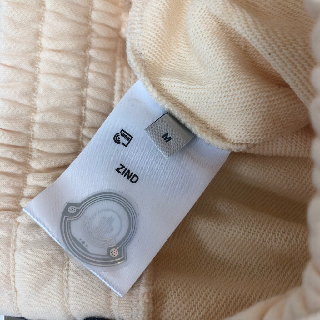 Interior fabric label showing size M and care icon, on cream shorts