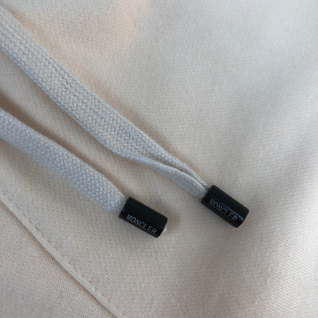 Cream drawstring cords with black tips labeled Moncler