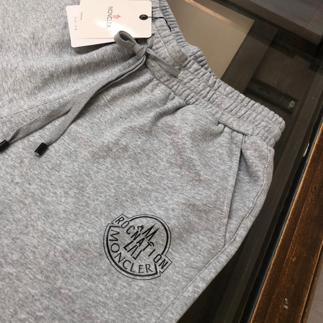 Light gray drawstring shorts with elastic waistband and circular logo patch on leg