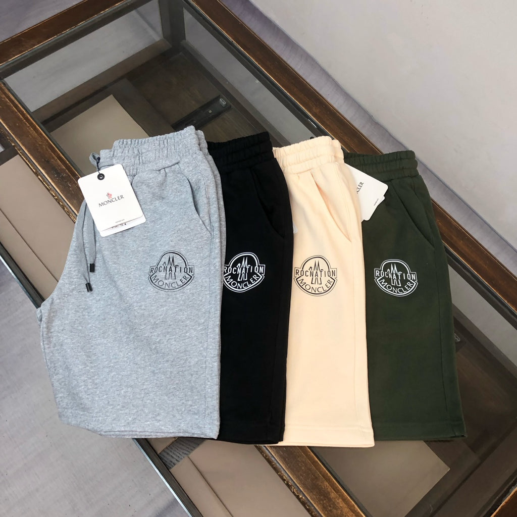 Set of four shorts: light gray, black, beige, and dark green, each with logo patch