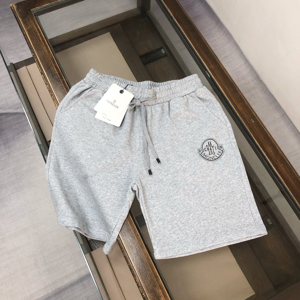 Light gray drawstring shorts with small circular logo patch and attached size tag
