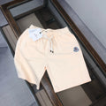 Cream drawstring shorts with elastic waistband and circular logo patch on leg