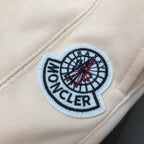 Circular fabric logo patch on cream shorts, with stitched border