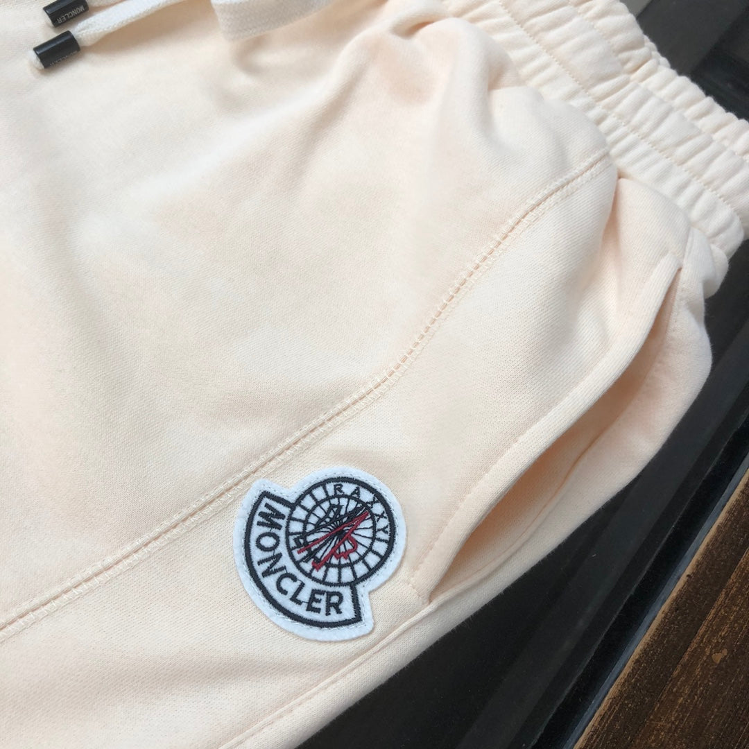 Cream shorts with elastic waistband, drawstring, and circular logo patch detail