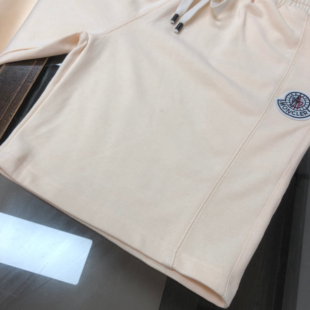 Cream shorts with elastic waist, side seam, and circular logo patch