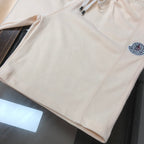 Cream shorts with elastic waist, side seam, and circular logo patch