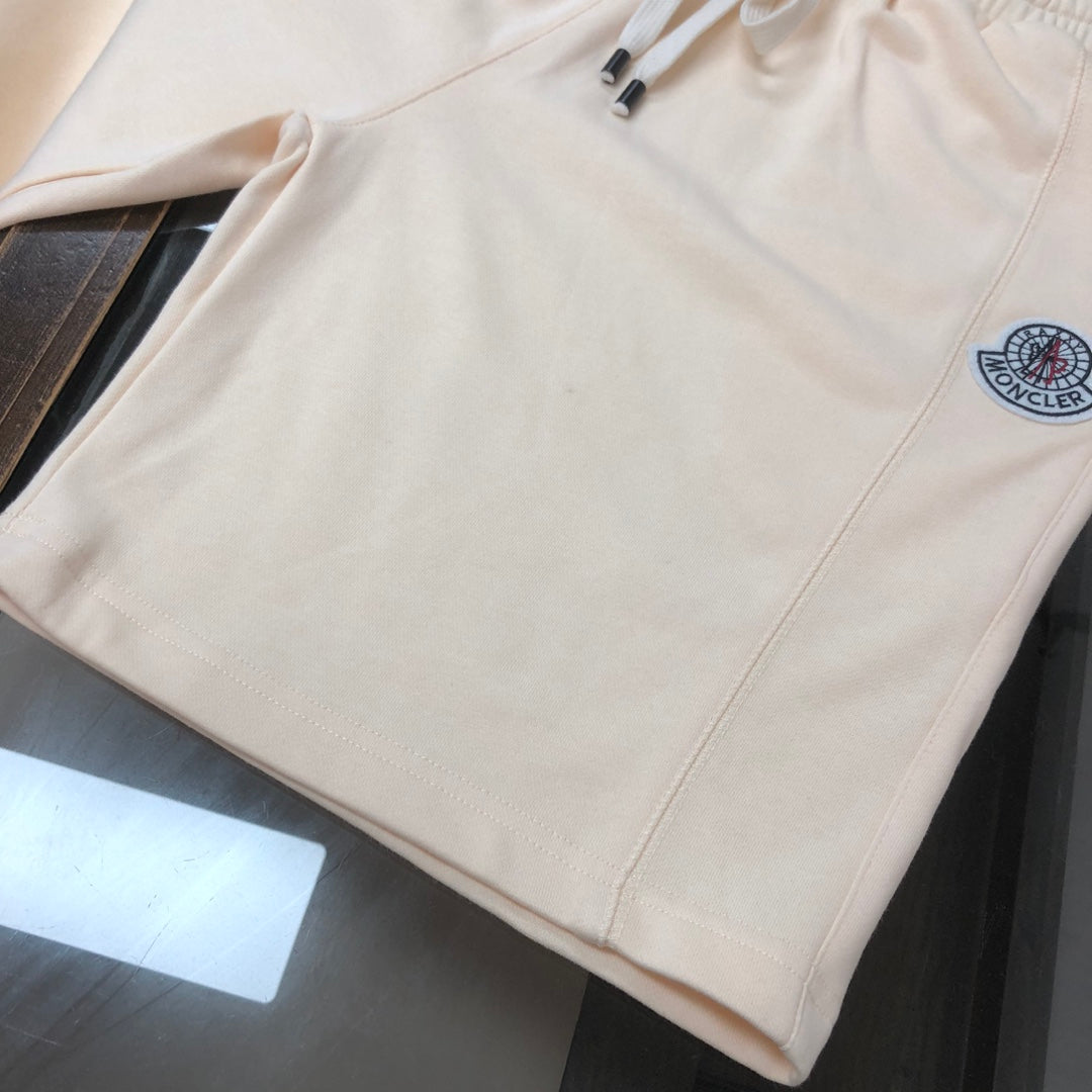 Cream shorts with elastic waist, side seam, and circular logo patch