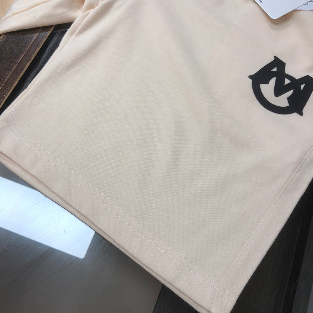 Cream shorts with black logo emblem on the front right leg