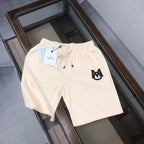 Cream drawstring shorts with elastic waistband and black front logo patch