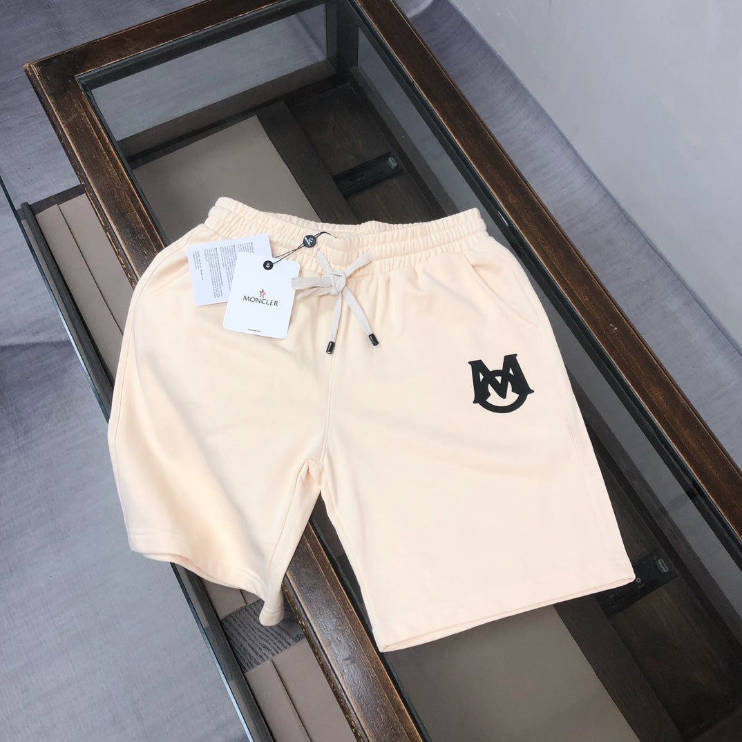 Cream drawstring shorts with elastic waistband and black front logo patch