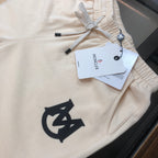Cream drawstring shorts close-up with black logo and hanging brand tags