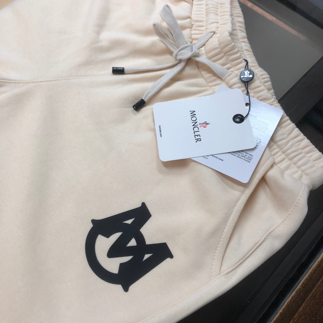 Cream drawstring shorts close-up with black logo and hanging brand tags