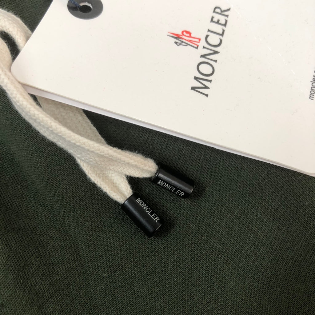 Dark green drawstring shorts with white MONCLER tag and small black logo patch