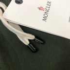 Dark green drawstring shorts with white MONCLER tag and small black logo patch