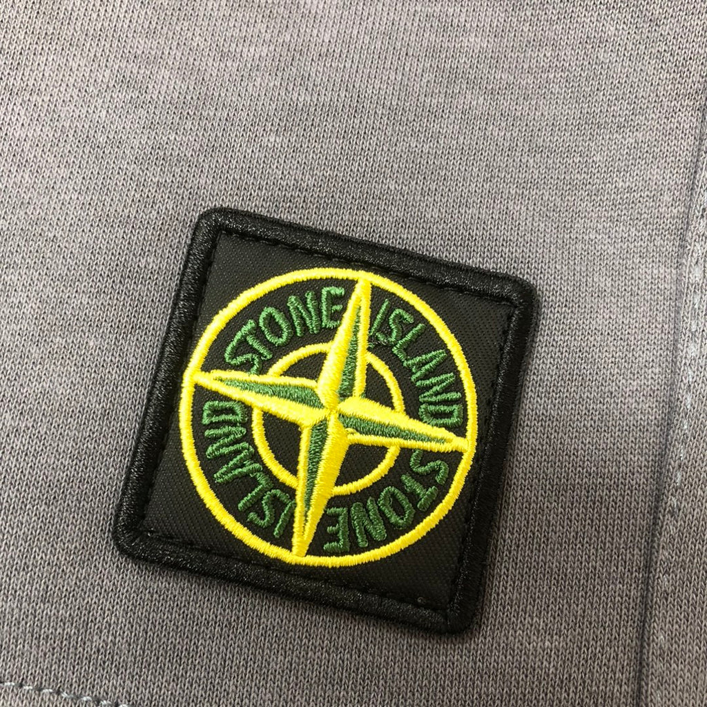 Embroidered Stone Island logo patch on gray fabric