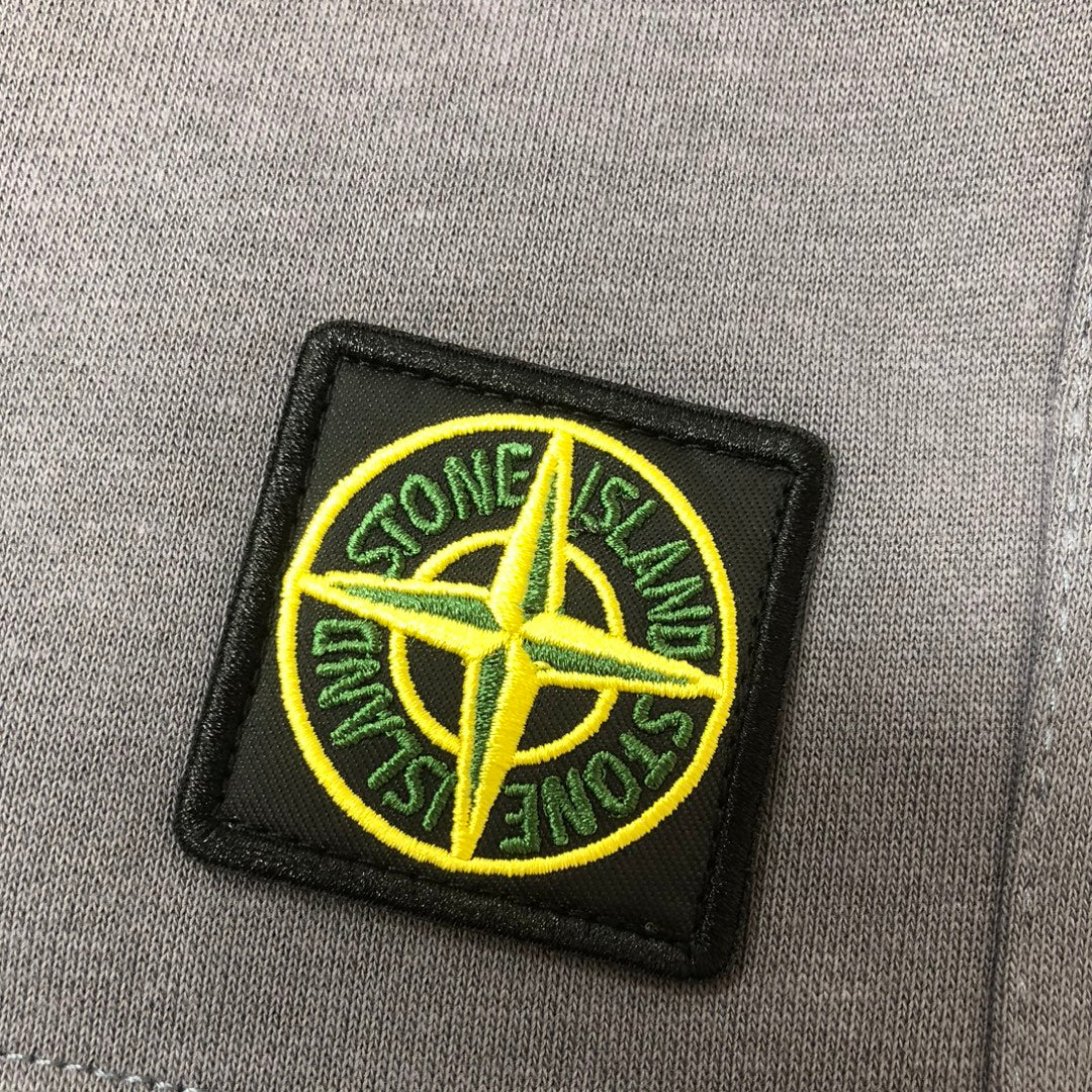 Embroidered Stone Island logo patch on gray fabric