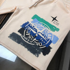 Stone Island cream shorts with large blue logo graphic and green paint stripe