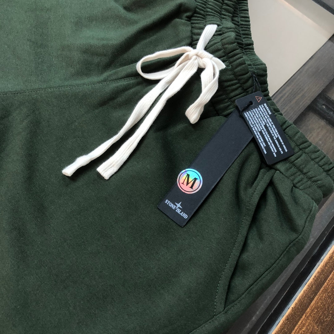 Green drawstring shorts close-up with white cords and Stone Island patch label