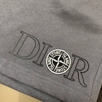 Gray shorts hem close-up with large Dior-style lettering and Stone Island badge
