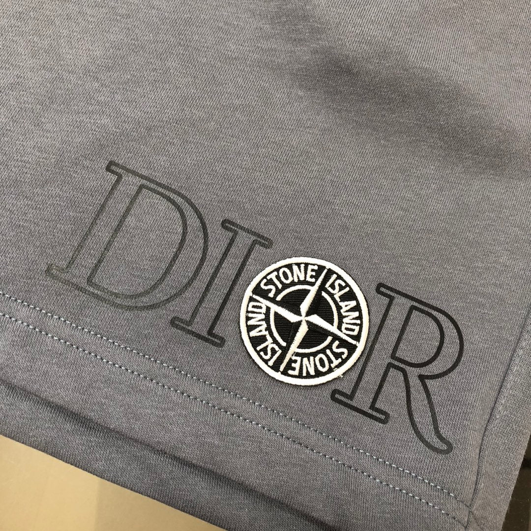 Gray shorts hem close-up with large Dior-style lettering and Stone Island badge