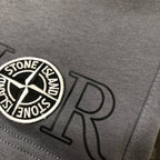Gray shorts close-up of circular Stone Island badge and dark logo lettering