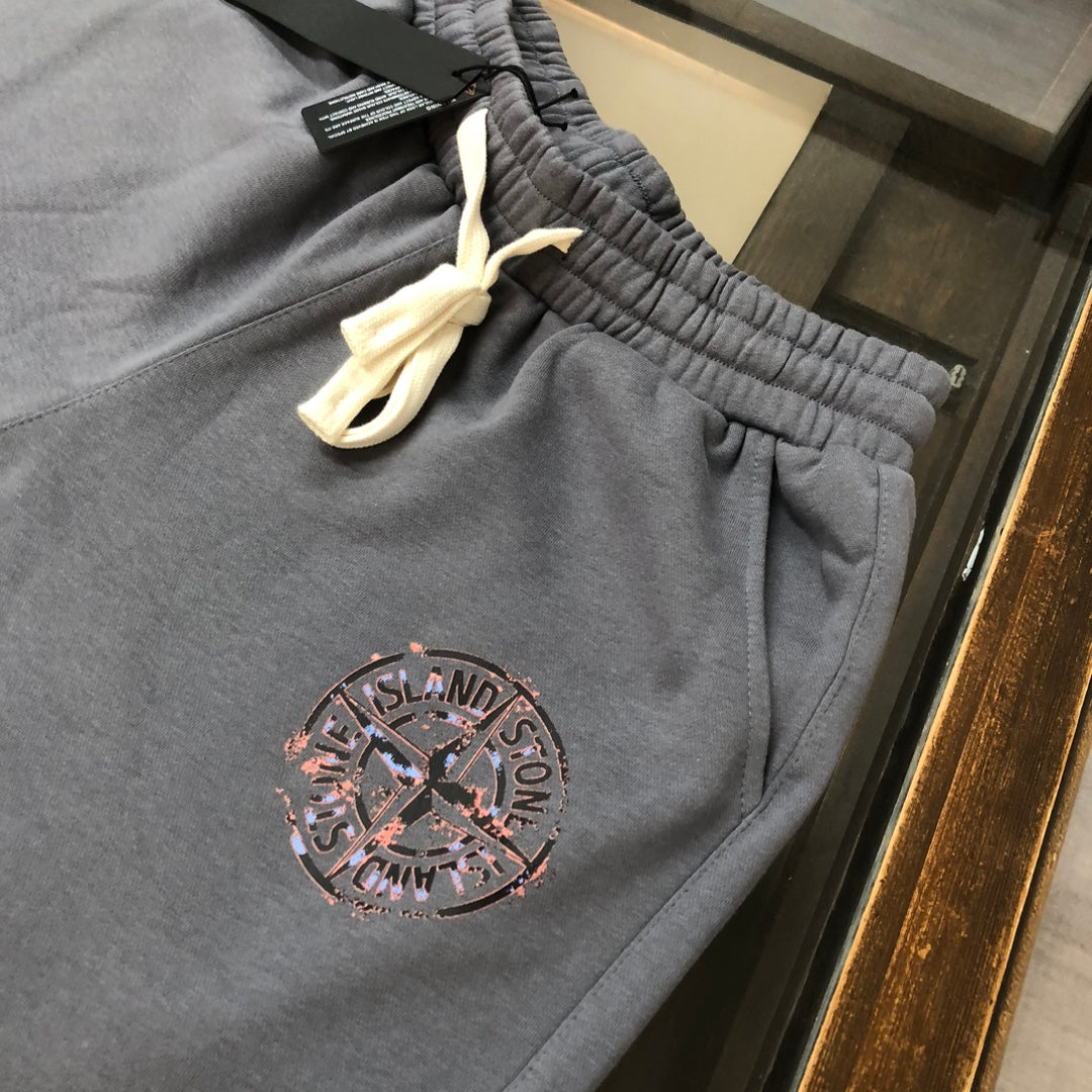 Dark gray Stone Island shorts with elastic waistband, yellow drawstring, and logo patch