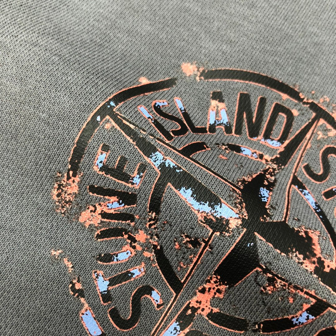 Close-up detail of Stone Island logo graphic patch on dark gray shorts