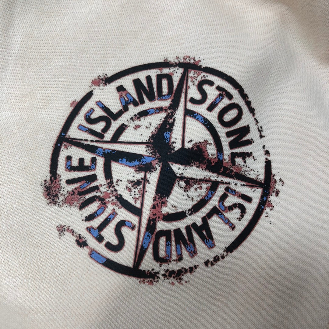 Close-up of circular Stone Island logo graphic on cream shorts fabric