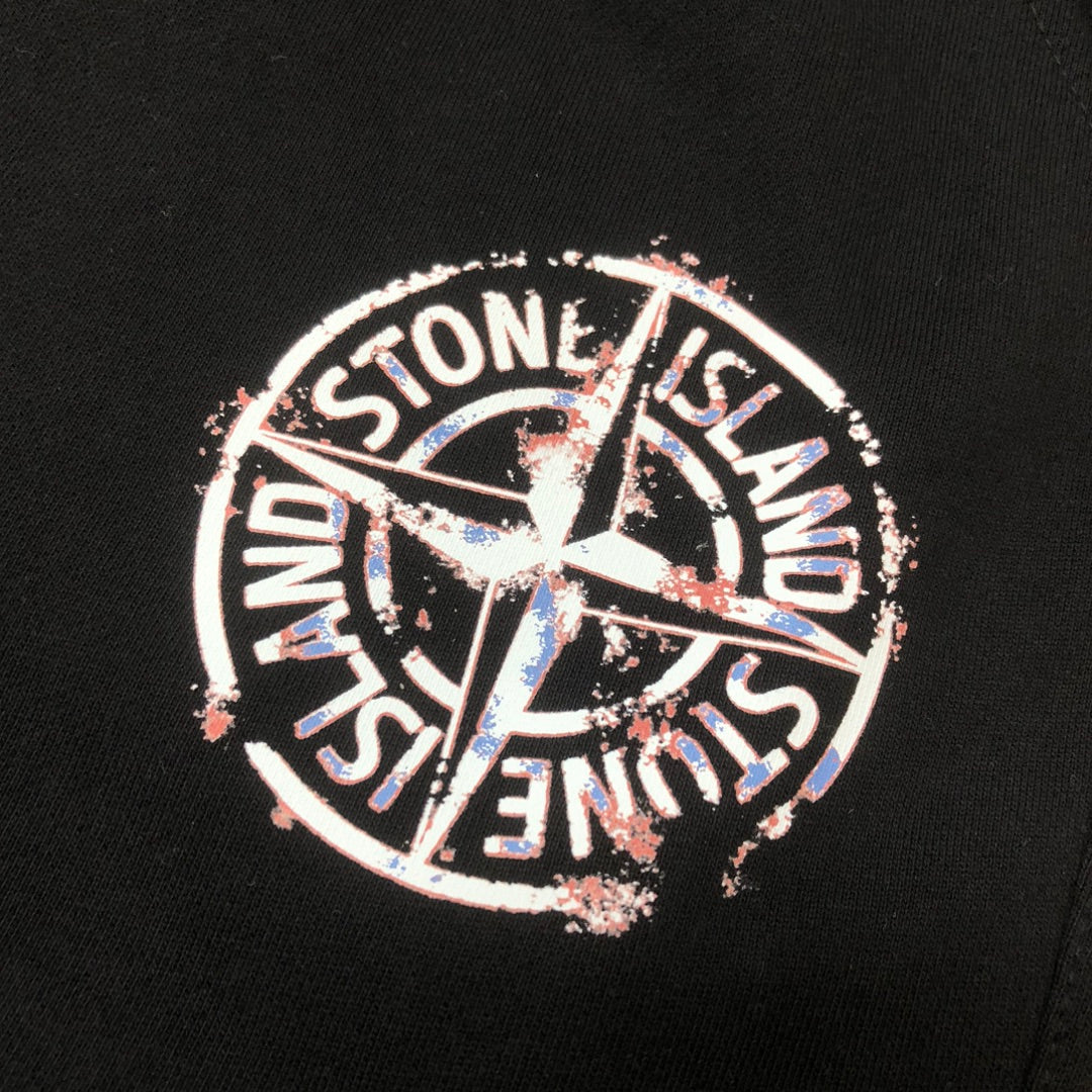 Stone Island circular logo patch on black shorts, featuring multicolor detailing