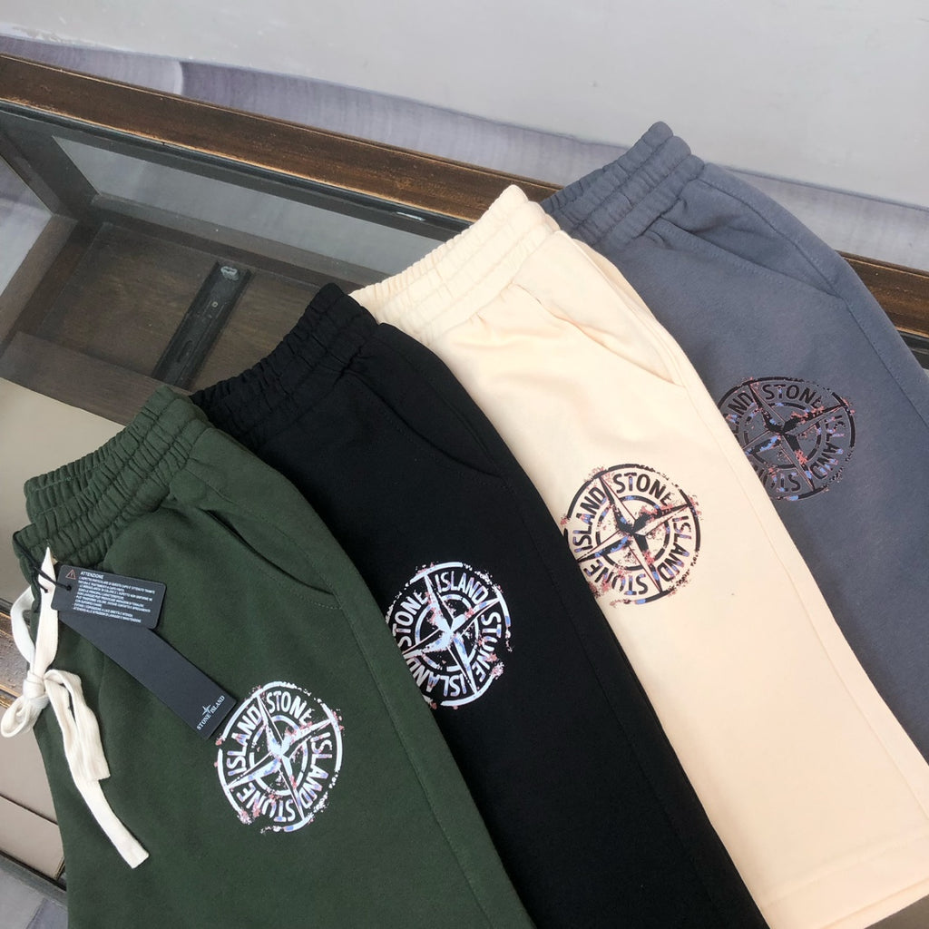 Three Stone Island shorts in dark, white, and green with circular logo patch and drawstring