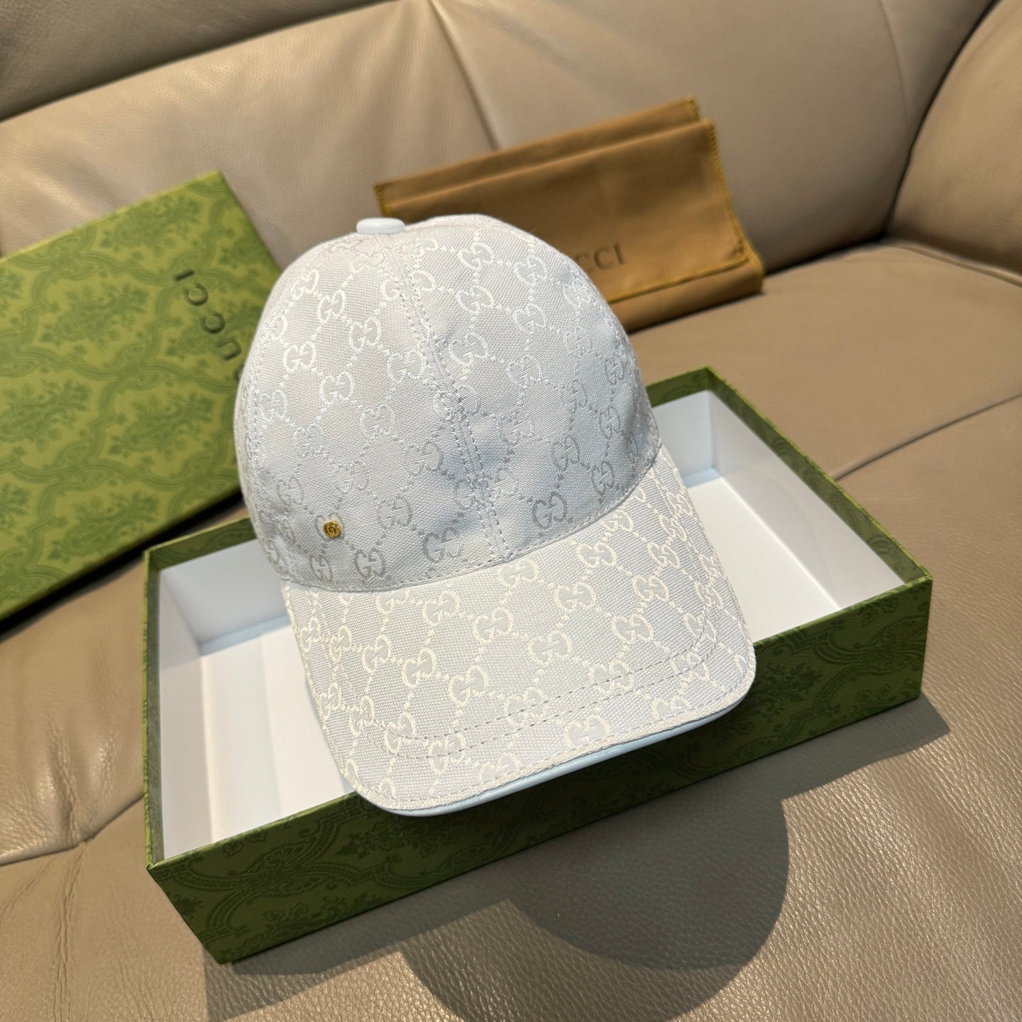 White Gucci cap with GG monogram pattern, curved brim, and small gold button detail
