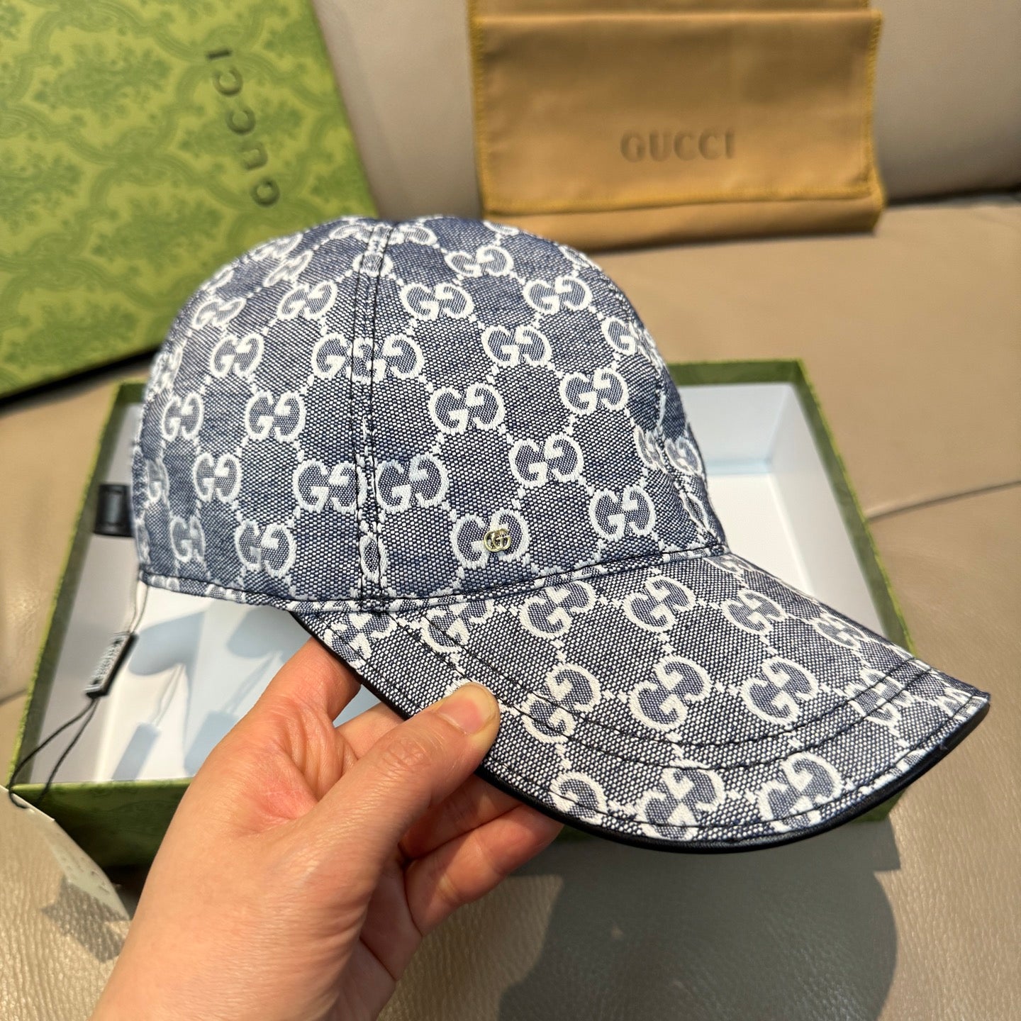 Gucci cap in dark blue with repeating GG monogram pattern, curved brim close-up in hand