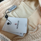Stone Island cream shorts with elastic waistband and hanging Moncler product tags