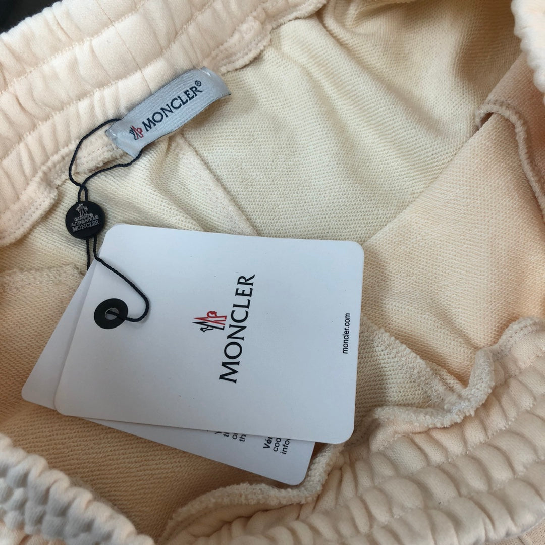 Stone Island cream shorts with elastic waistband and hanging Moncler product tags