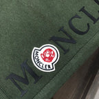Dark green Moncler shorts with large "MONCLER" logo print and emblem