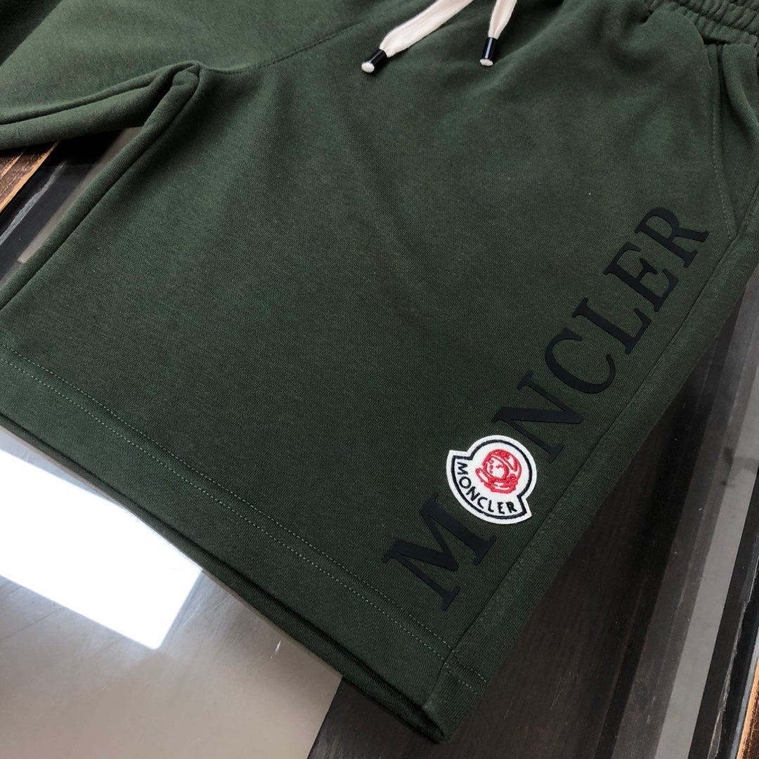 Dark green Moncler shorts with "MONCLER" print and circular logo patch