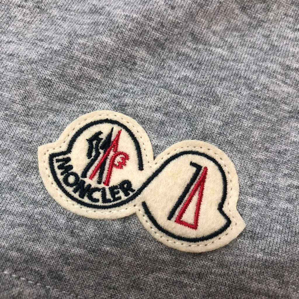 Embroidered logo patches on heather gray shorts fabric with beige borders